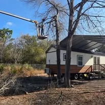 Excavated residential lot with graded earth, mature trees, and construction equipment on cleared site