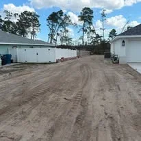 Graded dirt driveway with compacted soil and proper drainage slope on residential property