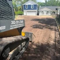 Excavated residential driveway site with compacted dirt base and service truck