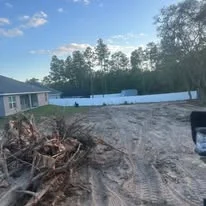 Excavated lot with cleared debris, exposed soil, and blue protective tarping