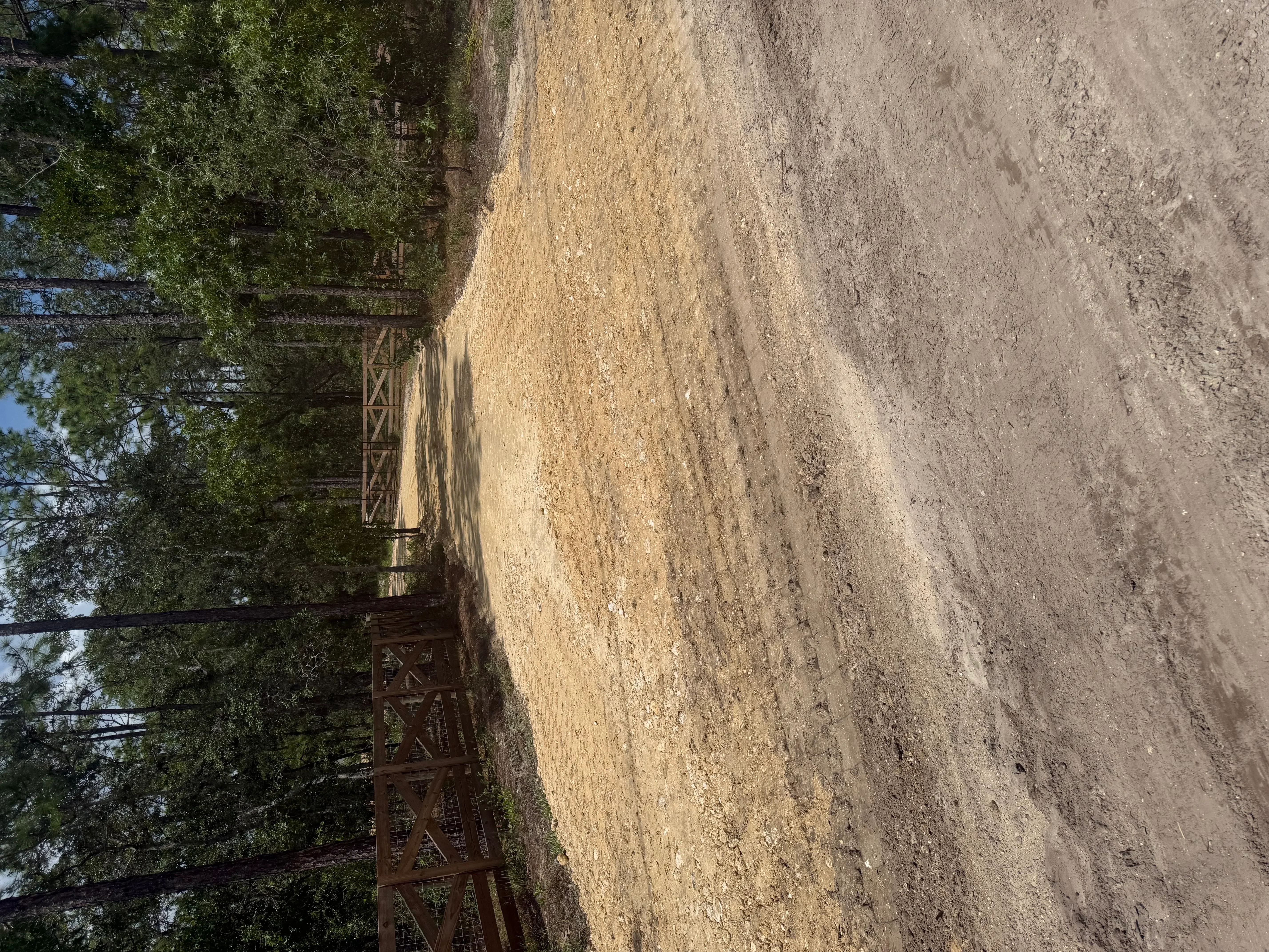 Excavated and graded driveway with compacted soil and metal gate entrance