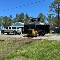 Asphalt milling machine removing pavement with support truck and crew on-site