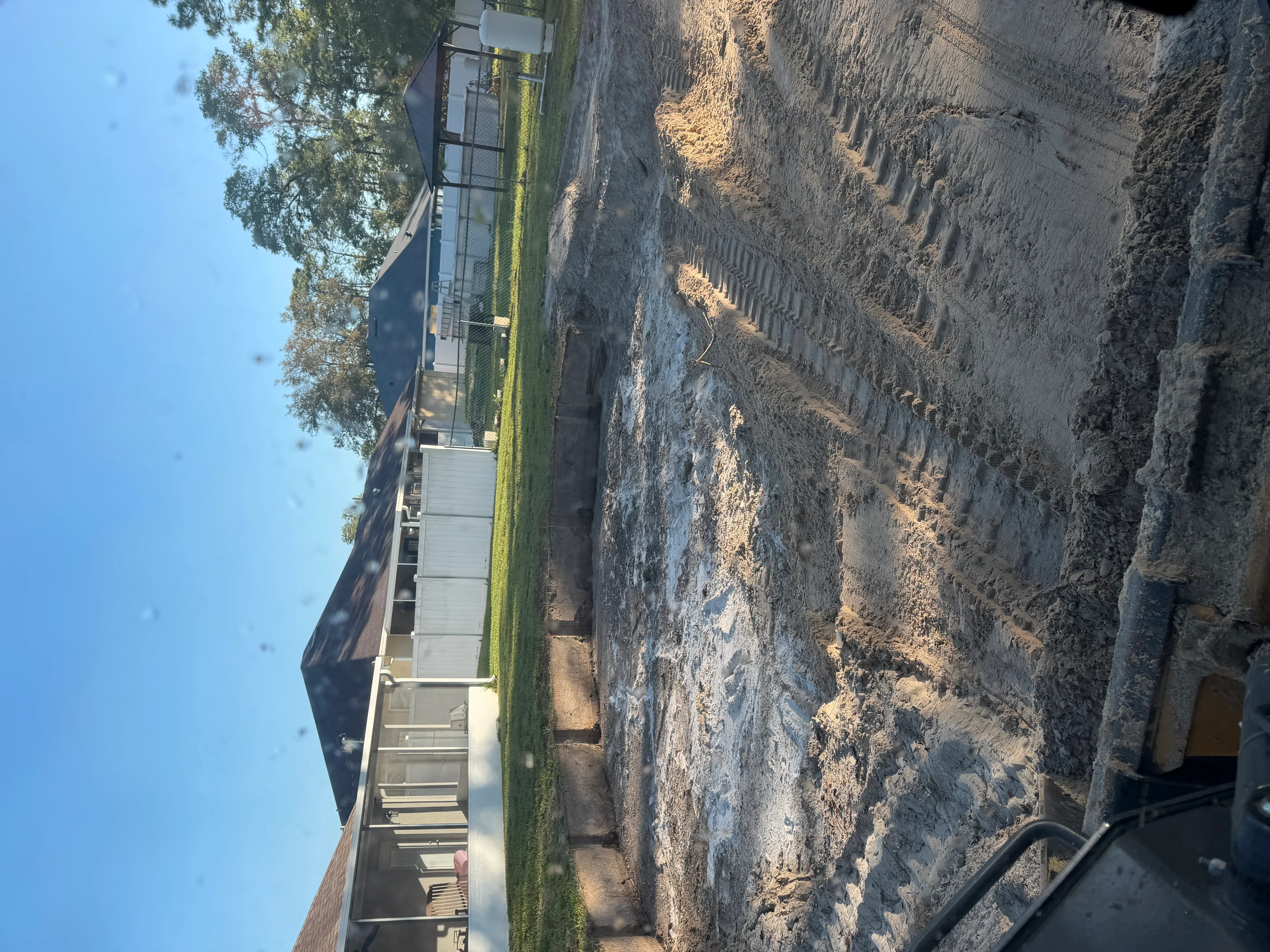 Excavated driveway site with graded soil banks and prepared subgrade for new installation