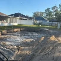 Excavated residential lot with trenched soil, grading work, and cleared foundation area