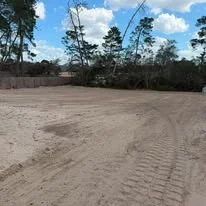 Excavated and graded dirt site with equipment tracks and level earthwork