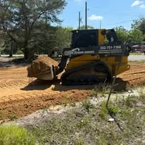 Compact track loader excavating and moving soil material on residential property