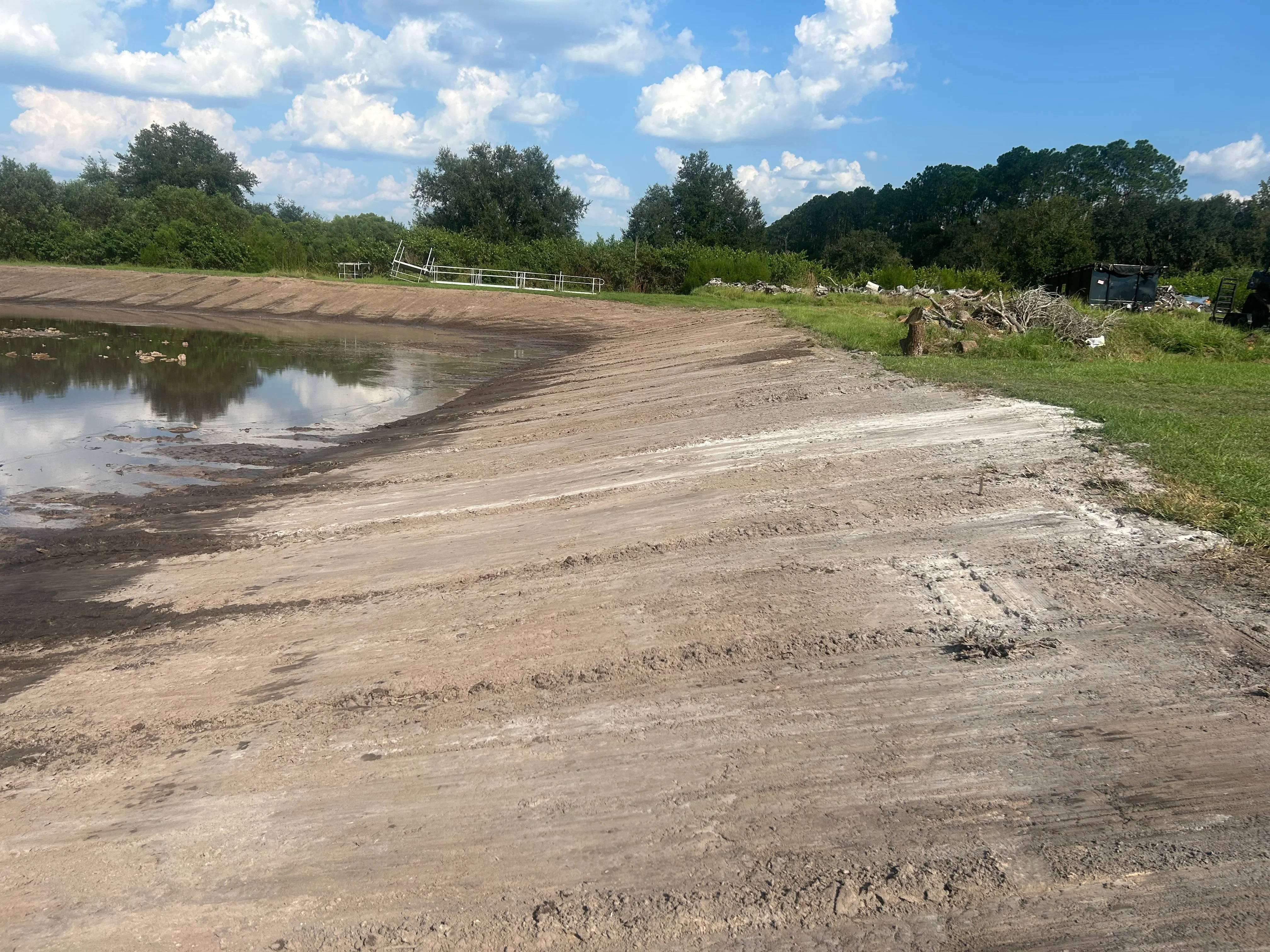 Graded dirt banks around pond with cleared access area and debris removal